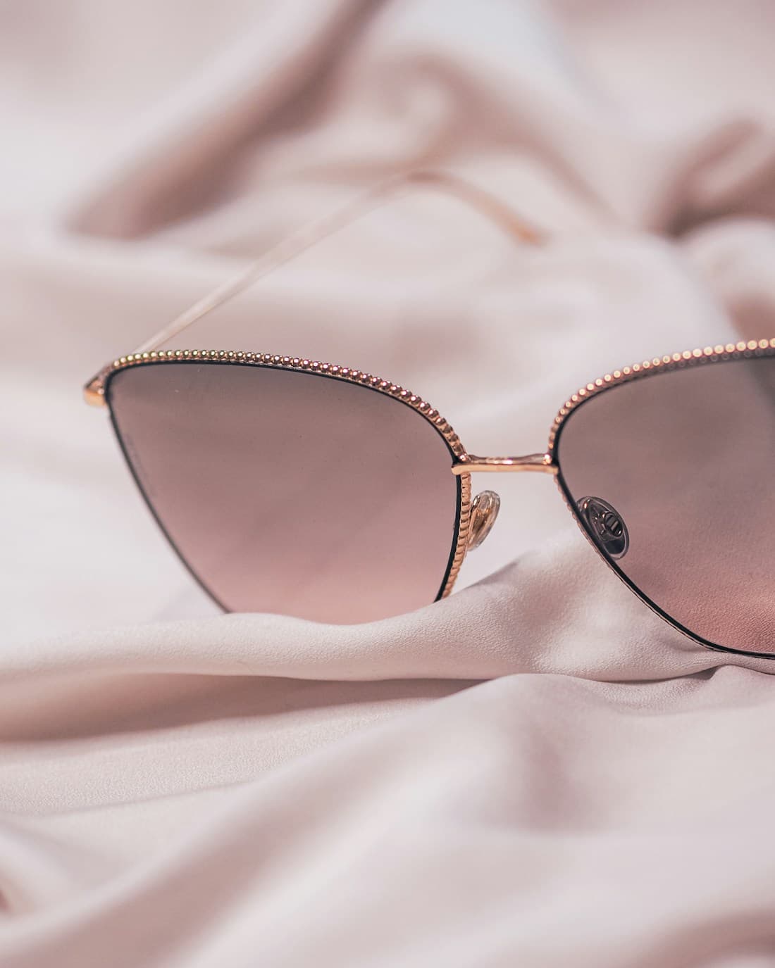 Rose-gold sunglasses resting on champagne silk — the See La Vie unwrapping moment